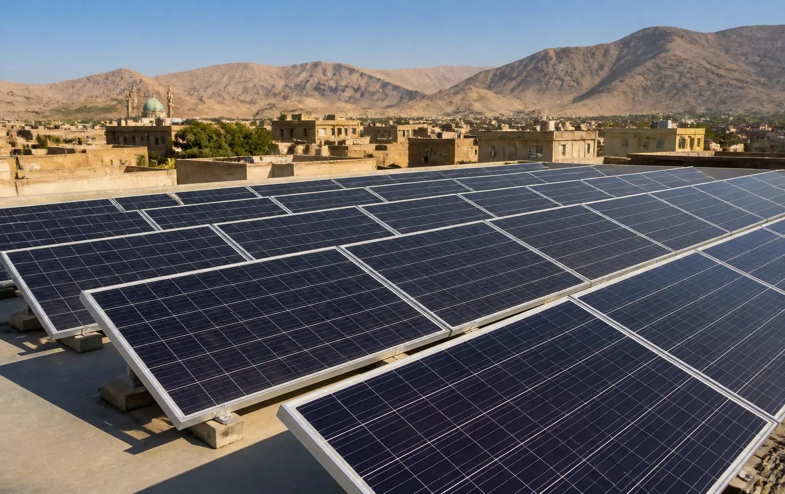 Solar panel array installed on a rooftop in Ghazni, Afghanistan with mountains behind